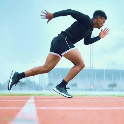 Sporter sprint op de atletiekbaan – focus op prestaties en herstel.